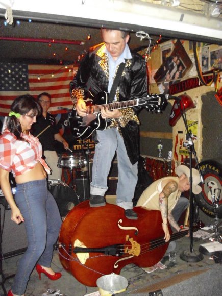 TANIA watches as MICK plays guitar as he stands on FIDDLES' bass as he plays it!