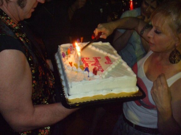 HENRY holds the cake as CYNDI tries to get it lit! (The air conditioner was blowing!)