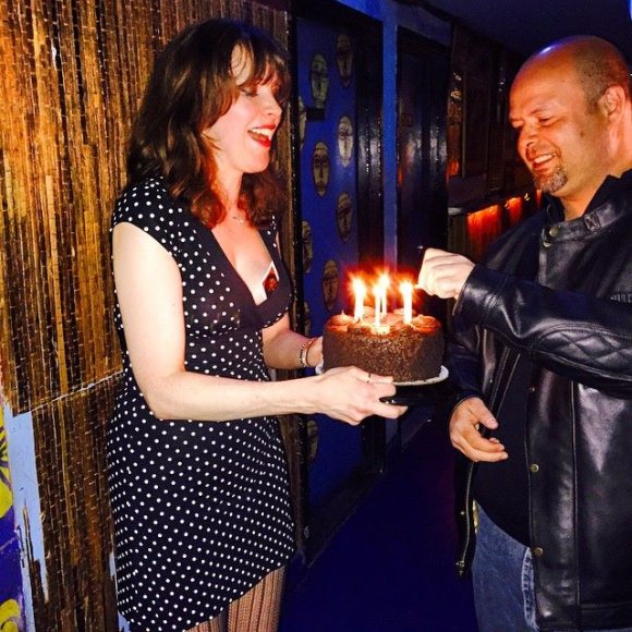 CHRISTA holds T. J.'s cake as STEVE B. lights then candles!